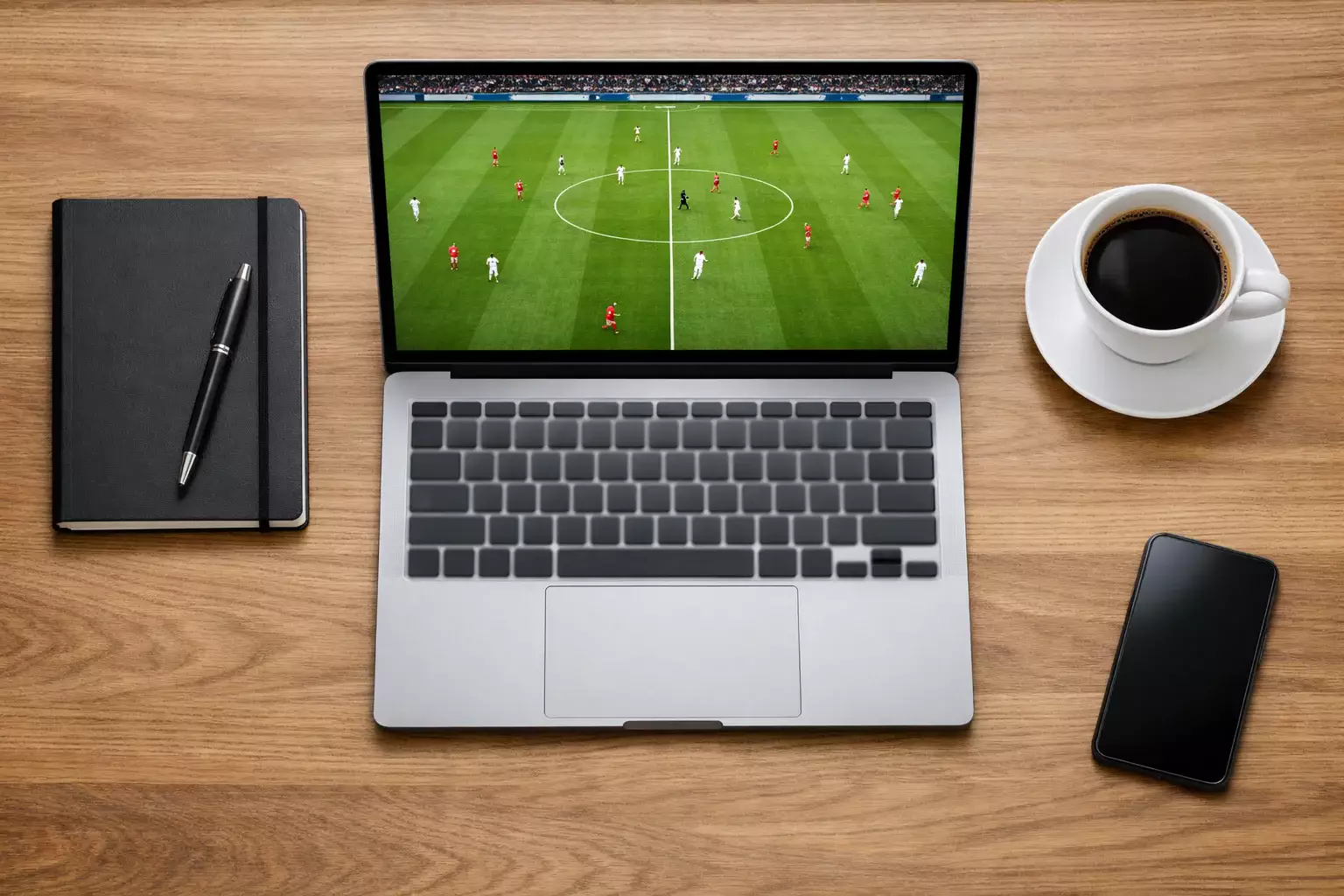 Laptop toont live voetbalstream naast notitieblok